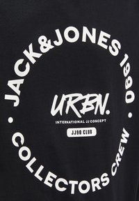Camiseta de algodón negra con texto blanco, incluyendo "JACK&JONES 1990" y "COLLECTORS CREW," en un diseño circular. Textura suave.