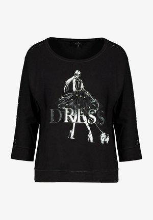 Musta collegepaita kolmen neljänneksen hihoilla, jossa on painettu kuvasto hameessa olevasta hahmosta ja sanasta "DRESS", jota korostavat kivet.