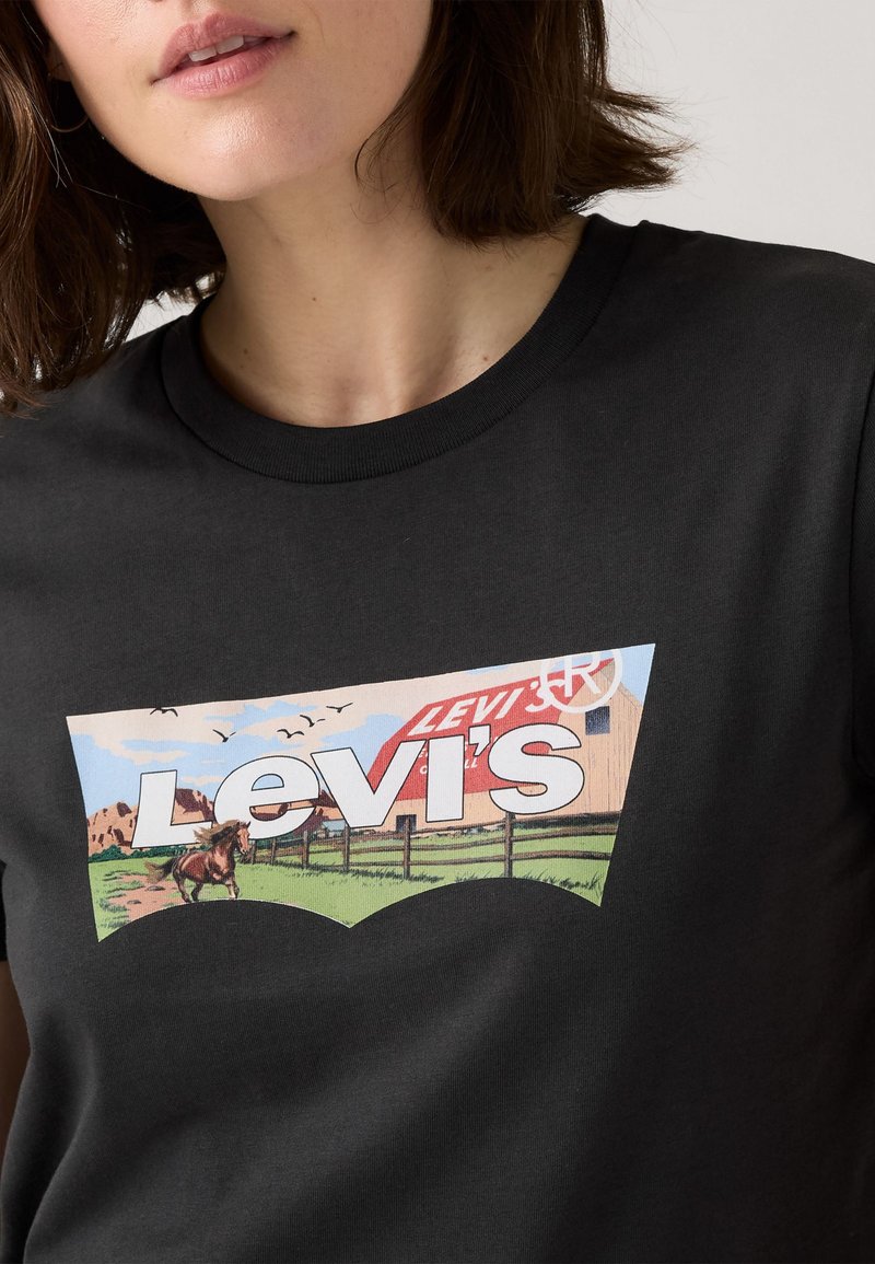 Czarny bawełniany t-shirt z kolorową grafiką przedstawiającą konia i stodołę, z napisem "Levi's", okrągłym dekoltem i krótkimi rękawami.