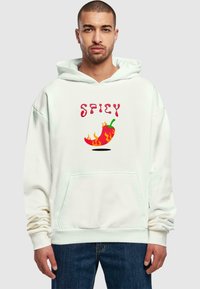 Felpa bianca con cappuccio caratterizzata dalla scritta "SPICY" in rosso e un grafico di peperoncino con fiamme, tasca anteriore a canguro e polsini a coste.