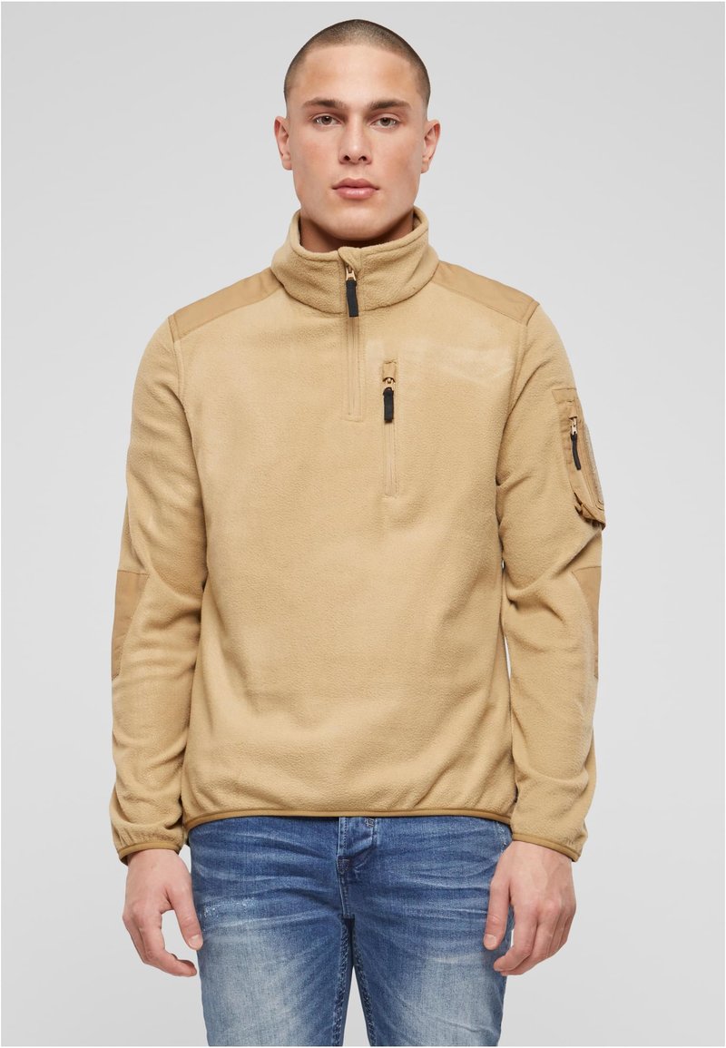 Barna polár pulóver magas gallérral, elülső félcipzárral és oldalzsebes cipzárral; vállakon kontrasztos panelekkel és puha tapintású anyagból.