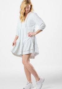 Hellblau und weiß gestreiftes Kleid mit Dreiviertelärmeln, einem V-Ausschnitt, einem ausgestellt gestuften Rock und dekorativen Lochmuster-Details.
