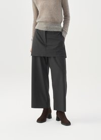 Dark gray wide-leg trousers with a layered design feature, made of a smooth fabric. Worn with a light, fuzzy beige sweater and heeled boots.