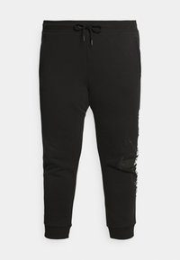 Schwarze Jogginghosen aus einem Baumwoll-Mischgewebe. Ausgestattet mit einem Kordelzugbund, gerippten Kn�öcheln und einem grafischen Design am linken Bein.
