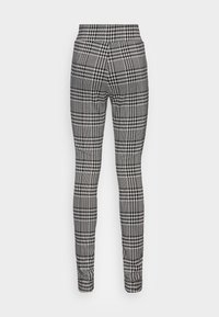 Pantalons à carreaux noir et blanc avec une coupe ajustée, présentant un motif pied-de-poule et une texture de tissu lisse. Taille haute.