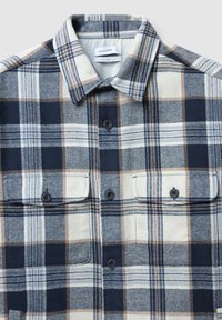 Camicia a quadri in blu navy, beige e azzurro chiaro con vestibilità comoda. Presenta due taschini sul petto e un colletto classico.