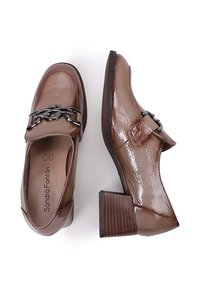 Mocassins en similicuir marron avec une finition texturée, un talon épais et un accent de chaîne décoratif sur le devant.