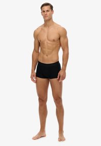 Boxers noirs en tissu doux avec une taille élastique. La coupe est ajustée et le design est simple et minimaliste.
