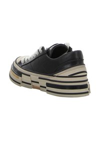 Schwarzer Ledersneaker mit klobiger beige Sohle, strukturierten Akzenten, weißen Schnürsenkeln und abgerundetem Zehenbereich. Sichtbares, mehrlagiges Sohlen-Design.