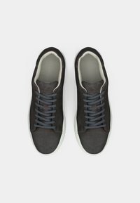 Mørkegrå semskede sneakers med lysegrå indvendig foring, flade grå snørebånd og en tekstureret hvid gummisål. Klassisk lavtop design.