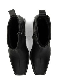 Par de botines negros de cuero con punteras cuadradas, cremalleras en el lado interno y tiradores en la parte trasera, mostrados desde una vista superior.