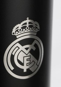 Czarna butelka o matowej teksturze z metalicznym srebnym herbem z koroną i splecionymi literami "RM".