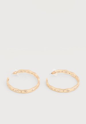 Náušnice v zlatej farbe s nepravidelným vlnitým dizajnom a osadené priezračnými kryštalickými akcentmi, zabezpečené plastovými západkami.