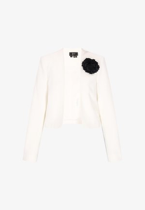 Blazer blanc sur mesure à manches longues, avec une épingle en forme de fleur en tissu noir sur le côté gauche de la poitrine, et un design sans col avec ouverture devant.