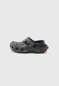 Black rubber clog featuring ventilation holes, adjustable back strap, and textured surface. Notable accents include yellow and red details.