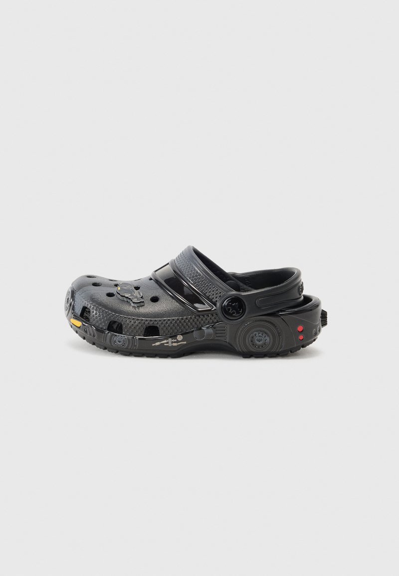 Black rubber clog featuring ventilation holes, adjustable back strap, and textured surface. Notable accents include yellow and red details.