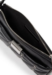 Fekete bőr clutch táska steppelt mintázattal, ezüst hardware-rel, cipzáros záródással és texturált belsővel, amely kártyatartót is tartalmaz.