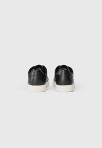 Sneakers din piele neagră cu un panou din spate texturat, talpă din cauciuc alb și un finisaj neted. Design simplu cu un branding minim pe călcâi.