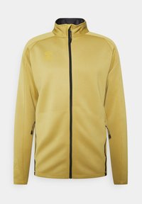 Żółta sportowa kurtka na pełny zamek błyskawiczny z wysokim kołnierzem, bocznymi kieszeniami na zamek, czarnym zamkiem i subtelnym logo marki na piersi.
