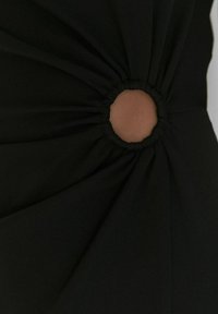 Robe noire avec un tissu froncé et une découpe circulaire, révélant la peau. Texture lisse et design structuré avec des lignes fines et élégantes.