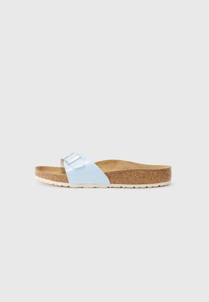 Sandale à bride unique bleu clair avec boucle ajustable, semelle intérieure en liège et semelle en caoutchouc blanc sur fond gris uni.