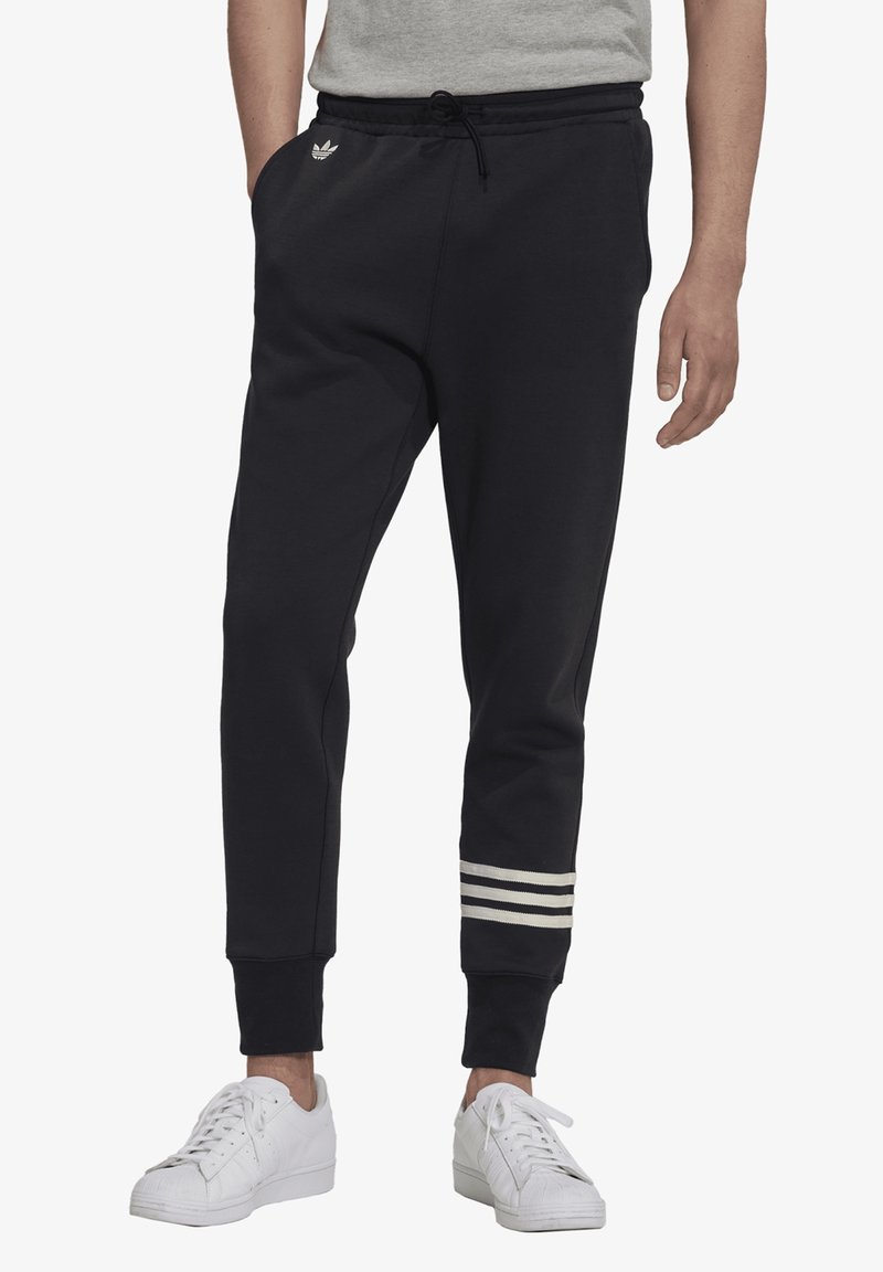 Navy jogger pants with elastic waistband, drawstring, side pockets, and white striped accents at the ankles. Soft fabric texture.