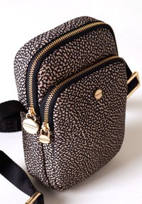 Borsa a tracolla in tessuto nero e beige con una texture, dotata di due zip dorate, finiture in oro e una tracolla nera regolabile.
