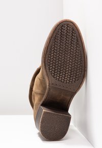 Bottine en daim marron avec une semelle en caoutchouc texturée, présentant un motif tissé et un petit talon carré. Taille 37 indiquée sur la semelle.