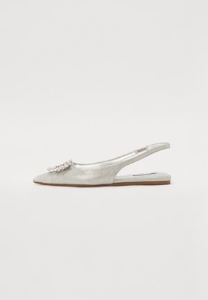 Scarpa bassa argentata con punta appuntita e cinturino posteriore, finitura scintillante e decorazione in strass davanti su sfondo uniforme.