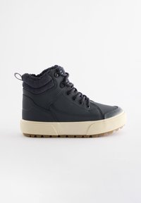 Chaussure montante noire avec semelle beige, col rembourré à la cheville, laçage à l'avant et semelle à crampons robustes, conçue pour un usage décontracté ou en extérieur.