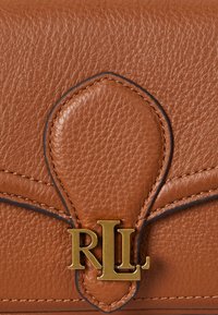 Rjava usnjena torbica z izbočenim robom, ki vsebuje zlat ton "RLL" logo in teksturirano površino. Podrobno šivanje poudarja obliko.
