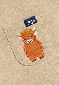 Beige Stofftasche mit besticktem orangefarbenem Highland-Rind und kleinem marineblauen Etikett mit der Aufschrift "JoJo" am oberen Rand.