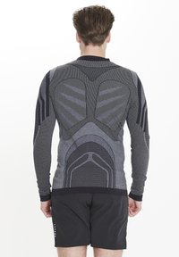 Långärmad idrottströja, grå mönstrad tyg med texturerade detaljer, med en åtsittande design och kontrasterande ärmdetaljer.