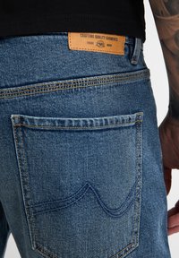 Blauwe spijkerbroeken van denimbaan met een gestructureerd oppervlak, voorzien van een enkele achterzak, zichtbare stiksels en een leren label in bruin bij de taille.