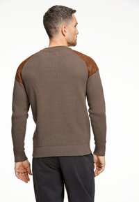 Maglione a coste marrone con dettagli in suede marrone sulle spalle. La vestibilità è casual, con maniche lunghe e scollatura rotonda.