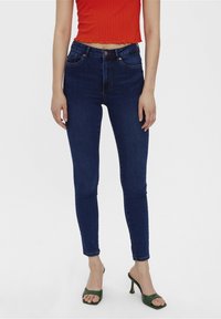 Jeans ajustados de tiro alto en azul, fabricados en denim con una textura suave; cuentan con bolsillos tradicionales y un cierre de botón frontal.