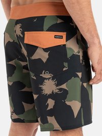 Herren Boardshorts in Schwarz mit grünem und beige floralem Camouflage-Muster. Mit einem braunen Bund und einer Gesäßtasche mit Markenlabel.