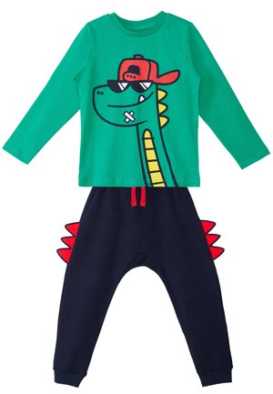 Maglietta verde a maniche lunghe con dinosauro fumettistico che indossa occhiali da sole e cappellino rosso, abbinata a pantaloni blu navy con punte rosse di dinosauro ai lati.