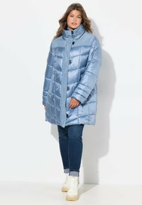 Abrigo acolchado azul claro con cuello alto, diseño acolchado y cierres de botones. La tela parece brillante, con bolsillos laterales.