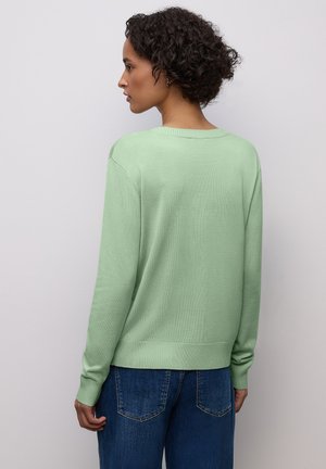 Light green sweater with a relaxed fit, featuring a round neckline, ribbed cuffs, and hem. Paired with blue denim jeans.