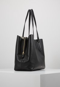Sort læder tote bag med en tekstureret overflade, udstyret med to lange håndtag og en guld lynlås lukning. Designet med en åben top og minimalistisk form.
