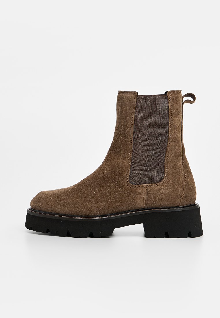 Braune Wildleder-Ankle-Boots mit elastischen Seiteneinsätzen, flacher schwarzer Plateausohle und Zugschlaufe. Mit einer abgerundeten Zehenpartie und minimalistischem Design.