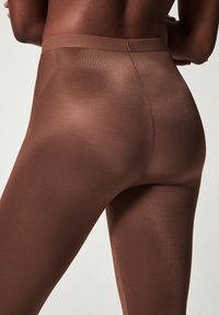 Brown leggings made of smooth, stretchy fabric with a high waistband, featuring subtle ribbed texture and a form-fitting design.