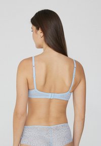 Sostenedor de encaje azul claro con tirantes ajustables, cierre de gancho, patrón floral y braga de encaje a juego, que muestra una textura suave.