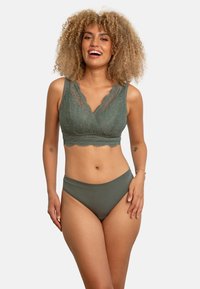 Grüne Spitzen-Bralette mit gewelltem Saum und V-Ausschnitt, kombiniert mit passenden hochgeschnittenen Panties aus einem glatten, dehnbaren Stoff.