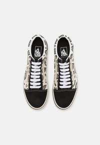 Sko med svart semsket tåhette og hvite snørebånd. Overdelen har et beige stoff med svarte paisleymønstre. Klassisk Vans-logo inni.