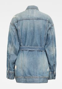 Chaqueta de mezclilla en azul claro, con cintura ajustable, puños con botones y detalles desgastados. Costuras visibles y diseño de cuello clásico.