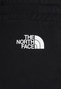 Tissu noir avec un logo blanc "THE NORTH FACE" et un motif en quart de cercle sur le côté droit.