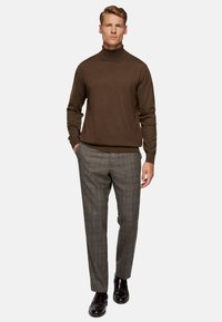 Brown turtleneck sweater paired with gray plaid trousers, complemented by black leather shoes. Smooth texture with a fitted design.