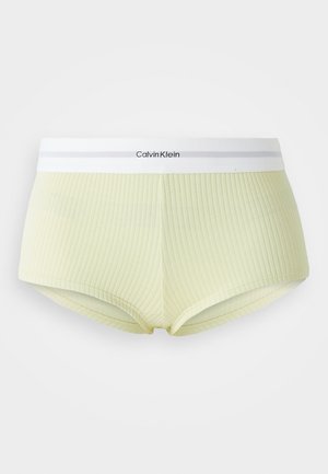 Bragas tipo boyshort de color amarillo claro con una cinturilla blanca de Calvin Klein. La cinturilla presenta una sutil franja gris y el logo.